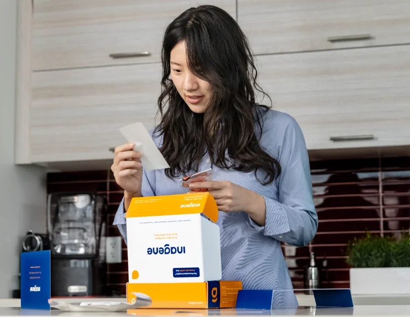 Person at a kitchen counter opening a branded product box, reading the insert